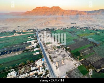 Erleben Sie das Erwachen der Memnon Kolosse, während die Sonne über Luxor aufgeht. Dieses Luftbild fängt die majestätischen Statuen in all ihrer Pracht ein. Stockfoto