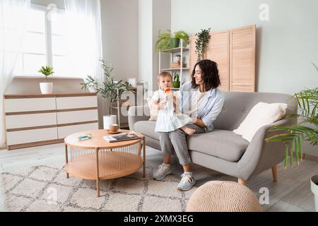 Mutter gibt ihrem kleinen Babyknabber zu Hause auf dem Sofa Stockfoto