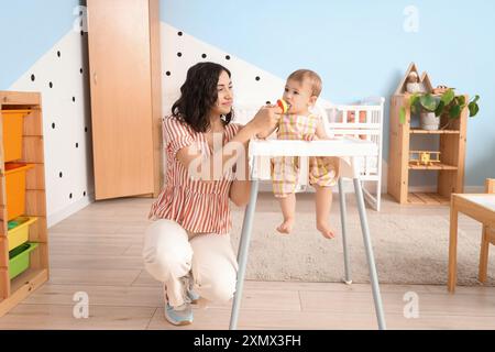 Mutter gibt ihrem kleinen Babyknabber im Schlafzimmer Essen Stockfoto