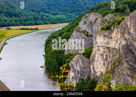 Meuse River und Felsformation bekannt als Freyr Rocks, zwischen Wiesen, Hügeln mit üppigen grünen Laubbäumen, unregelmäßigen Felswänden, berühmt für Klettertouren Stockfoto