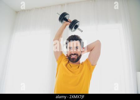 Foto eines attraktiven, netten, sportlichen starken Mannes, der körperliche Übungen macht, die harte schwere Ausrüstung im Haus trainieren Stockfoto