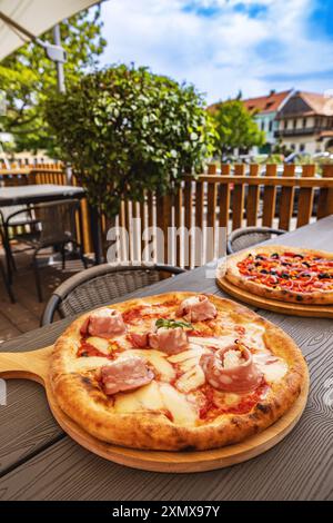 Köstliche Pizza, die auf Holzteller am Restauranttisch im Freien serviert wird Stockfoto