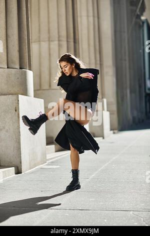 Eine junge Frau in schwarzem Outfit tanzt mit Anmut und Stil auf den Straßen von New York City. Stockfoto