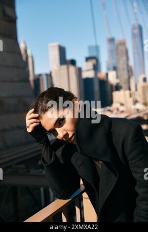 Eine junge Frau im schwarzen Mantel lehnt sich an ein Geländer in New York City. Stockfoto