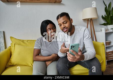 Ein Paar lächelt und lacht zusammen, während er auf ein Telefon schaut. Stockfoto