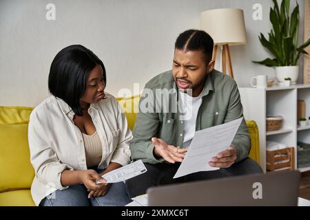 Ein afroamerikanisches Paar sitzt zu Hause auf einer Couch, überprüft Papiere und diskutiert Finanzen. Stockfoto
