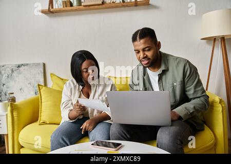 Ein afroamerikanisches Paar arbeitet zu Hause zusammen an einem Laptop. Stockfoto