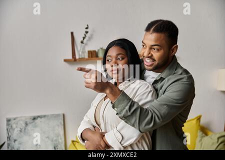 Das afroamerikanische Paar genießt einen gemütlichen Moment zu Hause, der Mann weist seinem Partner etwas zu. Stockfoto