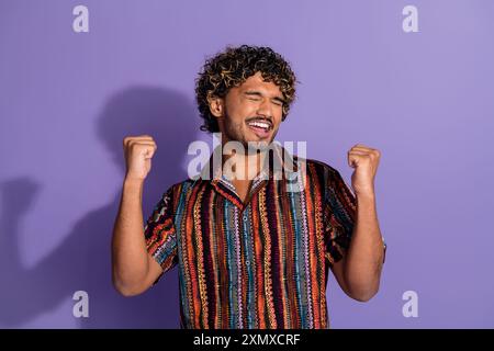 Porträt des netten jungen Mannes, die Fäuste tragen Hemd isoliert auf lila Hintergrund Stockfoto