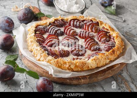 Frisch gebackener Pflaumenobstkuchen mit Mandeln auf einem Holzbrett auf dem Tisch. Horizontal Stockfoto