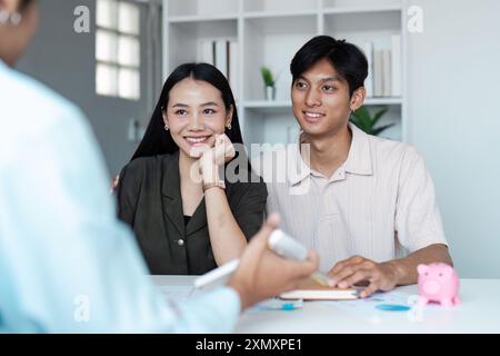 Junges Paar diskutiert Sparpläne mit Finanzberater im modernen Büroumfeld Stockfoto