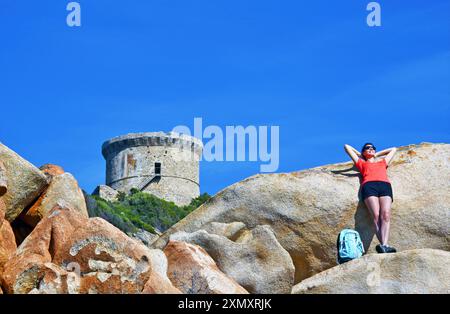 Junge Wandererin, die eine Pause auf dem Wanderweg am Genueser Turm von Campomoro, Frankreich, Korsika, Campomoro macht Stockfoto