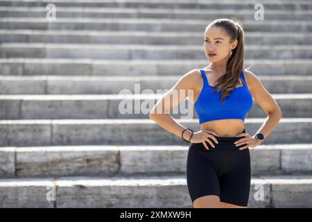 Foto einer attraktiven jungen Frau, die während ihres Trainings im Park eine Pause macht. Stockfoto