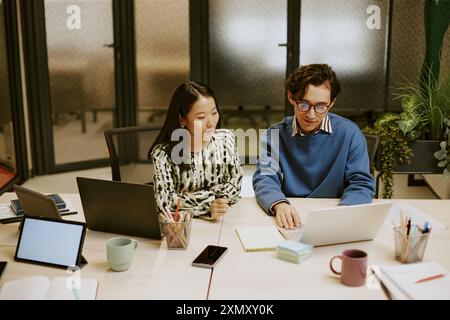 Hochwinkelansicht junger Spezialisten, die im Büro an der Präsentation auf Laptop arbeiten Stockfoto