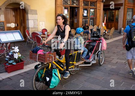 Frau Mutter und Kinder fahren Fahrrad und Anhänger in Annecy, Frankreich Stockfoto