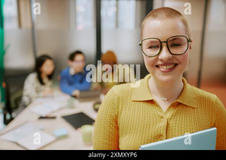 Mittelgroße Nahaufnahme einer fröhlichen jungen, stilvollen Büroangestellten mit Buzz-Haarschnitt, die im Sitzungszimmer stand und in die Kamera lächelte Stockfoto