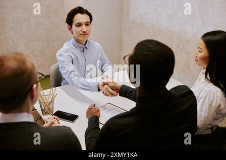 Hochwinkelansicht eines jungen männlichen Bewerbers für ein Bewerbungsgespräch mit Grußfachleuten Stockfoto