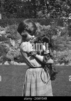 Mädchen, das einen Hund in einem Garten hält Stockfoto