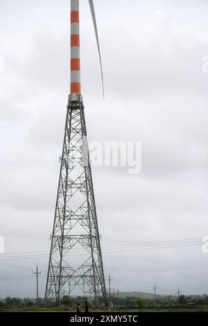 Eine majestätische Windenergieanlage erhebt sich hoch über dem bewölkten Himmel, deren drei Rotorblätter positioniert sind, um die Energie des Windes zu nutzen. Dekoriert mit Orange und wh Stockfoto