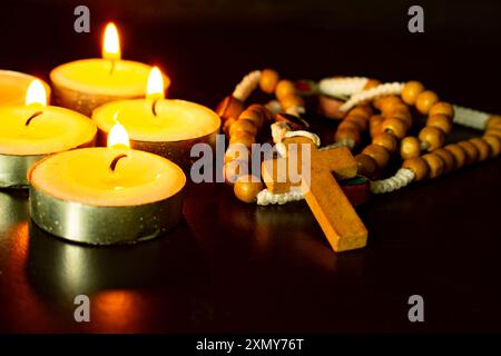 Kerzen mit heiligem Rosenkranz auf dunklem Hintergrund. Christentum-Konzept. Stockfoto