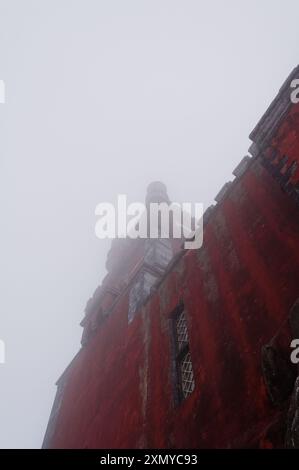 Der beeindruckende rote Uhrenturm des Pena Palace durchdringt den dicken Nebel an einem nebeligen Tag Stockfoto