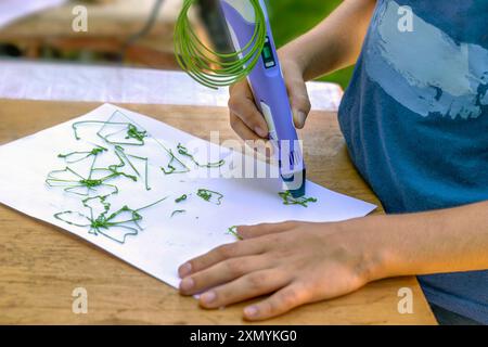 Junge zeichnet Figuren mit 3D-Stift auf Papier. Nahaufnahme. Stockfoto