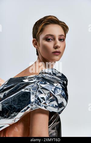 Eine Frau in silbernem, nachhaltigem Modekleid schaut aufmerksam in die Kamera. Stockfoto