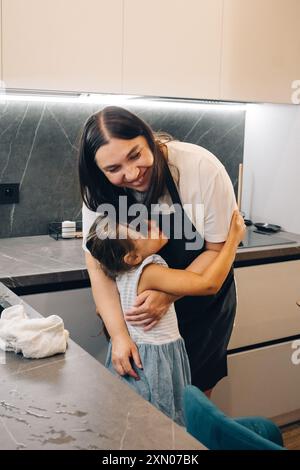 Ein herzerwärmender und berührender Moment zwischen einer liebevollen Mutter und ihrem Kind in einer gemütlichen Küche. Glückliche Familie genießt Momente des Kochens zu Hause. Stockfoto