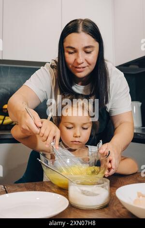 Eine Mutter und ihr Kind kochen gerne zusammen in ihrer modernen Familienküche. Glückliche Familie genießt Momente des Kochens zu Hause. Stockfoto