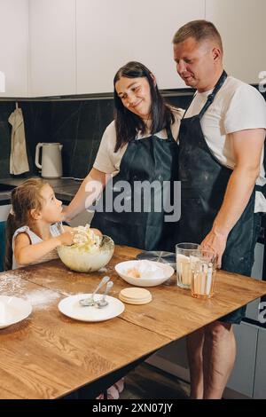 Eine Familie genießt es, gemeinsam in ihrer gemütlichen und einladenden Küche und Atmosphäre zu backen. Glückliche Familie genießt Momente des Kochens zu Hause. Stockfoto