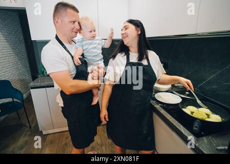 Eine reizvolle Szene, in der eine Familie die Zeit zusammen in ihrer modernen Küche kocht. Glückliche Familie genießt Momente des Kochens zu Hause. Stockfoto