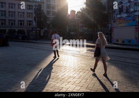 Ein Mann und eine Frau werfen Schatten auf ihrem Morgenspaziergang zur Arbeit in den ruhigen Straßen Amsterdams, Niederlande. Stockfoto