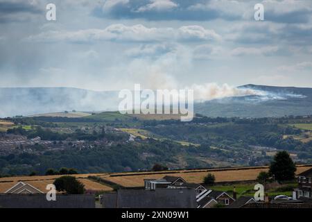 Huddersfield, West Yorkshire, Großbritannien, 30. Juli 2024 Eine Rauchwolke zieht durch die Landschaft von Pennine in der Nähe von Huddersfield, West Yorkshire, Großbritannien, als an einem der heißesten Tage des Jahres im Vereinigten Königreich ein Moorfeuer auf dem Marsden Moor brennt. Quelle: Windmill Images/Alamy Live News Stockfoto