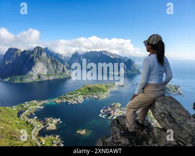 Ein atemberaubender ausblick von einem felsigen Gipfel aus, der die atemberaubenden Lofoten-Inseln, umgeben von glitzerndem Wasser unter einem klaren blauen Himmel, zeigt. Reinebringen Lofoten Norwegen Stockfoto
