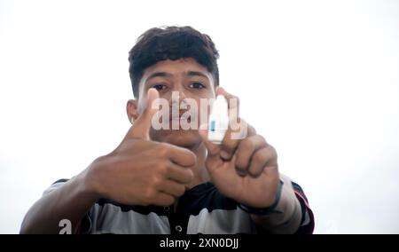 Augengrippe, Patient mit akuter Konjunktivitis, asiatischer Patient hat rote Augen und fühlt Schmerzen, Infektion Auge, Daumen hoch mit Augentropfen Stockfoto