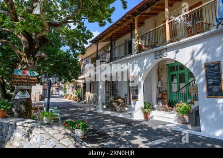 Eine schattige Straße und Taverne im oberen Teil des Dorfes Langadia (Lagkadia), Gortynia, Arcadia, Zentrum des Peloponnes, Griechenland. Stockfoto