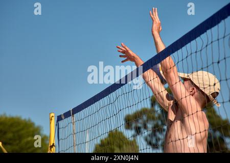 Während des 3x3 Ladeira Beach Volleyball Turniers in Baiona springen die Spieler mit erhobenen Armen und führen einen mächtigen Block in die ne aus Stockfoto
