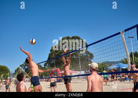 Während des 3x3 Ladeira Beach Volleyball Turniers in Baiona springen die Spieler mit erhobenen Armen und führen einen mächtigen Block in die ne aus Stockfoto