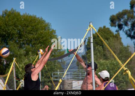 Während des 3x3 Ladeira Beach Volleyball Turniers in Baiona springen die Spieler mit erhobenen Armen und führen einen mächtigen Block in die ne aus Stockfoto