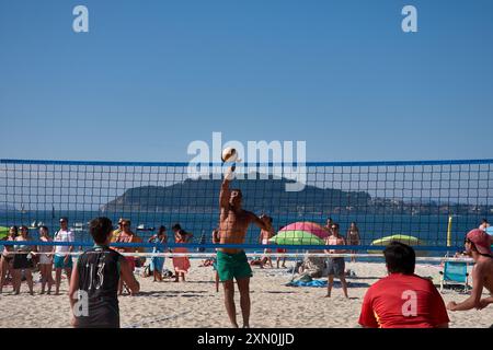 Während des 3x3 Ladeira Beach Volleyball Turniers in Baiona springen die Spieler mit erhobenen Armen und führen einen mächtigen Block in die ne aus Stockfoto