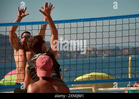 Während des 3x3 Ladeira Beach Volleyball Turniers in Baiona springen die Spieler mit erhobenen Armen und führen einen mächtigen Block in die ne aus Stockfoto