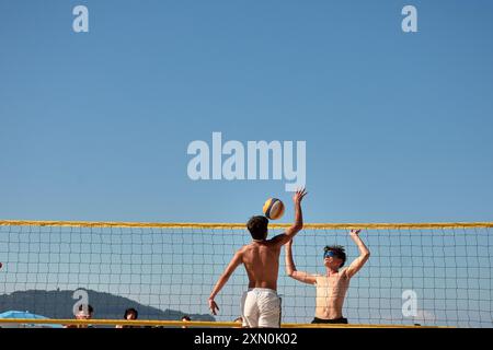 Während des 3x3 Ladeira Beach Volleyball Turniers in Baiona springen die Spieler mit erhobenen Armen und führen einen mächtigen Block in die ne aus Stockfoto