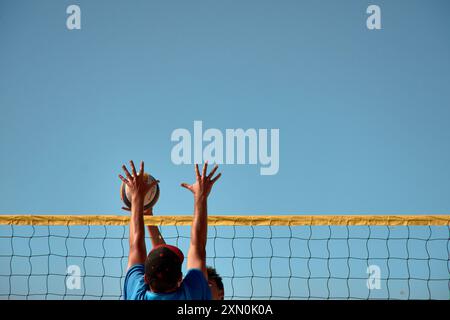Während des 3x3 Ladeira Beach Volleyball Turniers in Baiona springen die Spieler mit erhobenen Armen und führen einen mächtigen Block in die ne aus Stockfoto