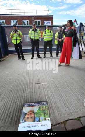 30. Juli 2024, Shenstone, England, Vereinigtes Königreich: Polizeibeamte bilden eine Absperrung über die Tore der UAV-Motorenfabrik, während während der Demonstration Sprecher die Menge ansprechen. Die Demonstranten fordern, dass UAV-Motoren keine Teile für Drohnen herstellen, die gegen das palästinensische Volk in Gaza und anderswo eingesetzt werden. Bei den israelischen Bombenanschlägen im Gazastreifen sind seit Oktober 2023 mehr als 35.000 Palästinenser ums Leben gekommen. Die Demonstranten, einschließlich Unterstützer der pro-palästinensischen Gruppe Palestine Action, sind entschlossen, Elbit und ihre Partnerunternehmen durch regelmäßige Proteste und direkte Aktionen unerbittlich ins Visier zu nehmen und Geschäfte für sie zu machen Stockfoto