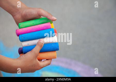 Kreidestäbchen. Große farbige Buntstifte in Kinderhänden. Das Kind hält die Kreide. Kopierbereich für den Hintergrund der Schule Stockfoto