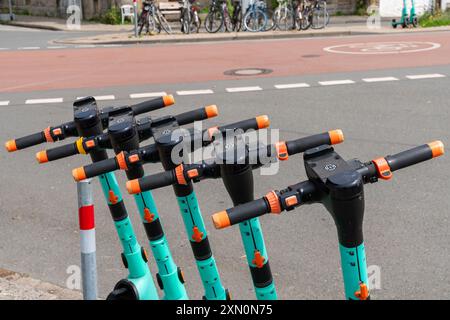 Fünf Elektroroller stehen ordentlich auf dem Bürgersteig und können an einem sonnigen Tag in einem Stadtgebiet eingesetzt werden. Stockfoto