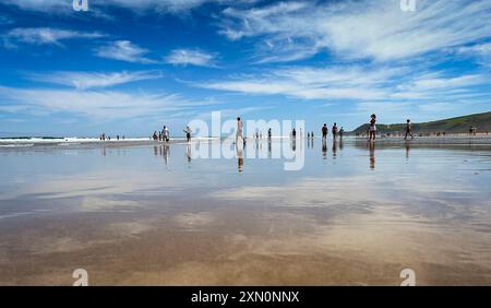 Panoramablick auf den Strand von Gerra, in Kantabrien. Mit dem Himmel und einigen Leuten, die am Strand spazieren und sich im nassen Sand spiegeln. Stockfoto