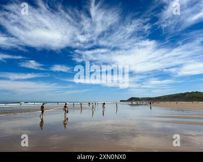 Panoramablick auf den Strand von Gerra, in Kantabrien. Mit dem Himmel und einigen Leuten, die am Strand spazieren und sich im nassen Sand spiegeln. Stockfoto