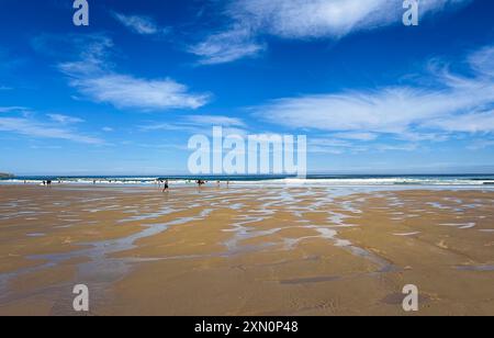 Panoramablick auf den Strand von Gerra, mit blauem Himmel und weißen Wolken, einige Leute laufen am Strand in der Ferne und im Vordergrund des Sandes. Stockfoto