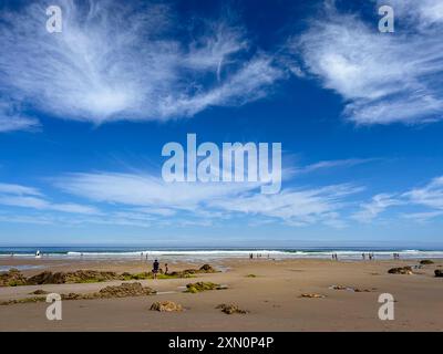 Panoramablick auf den Strand von Gerra, mit blauem Himmel und weißen Wolken, einige Leute laufen am Strand in der Ferne und im Vordergrund des Sandes. Stockfoto